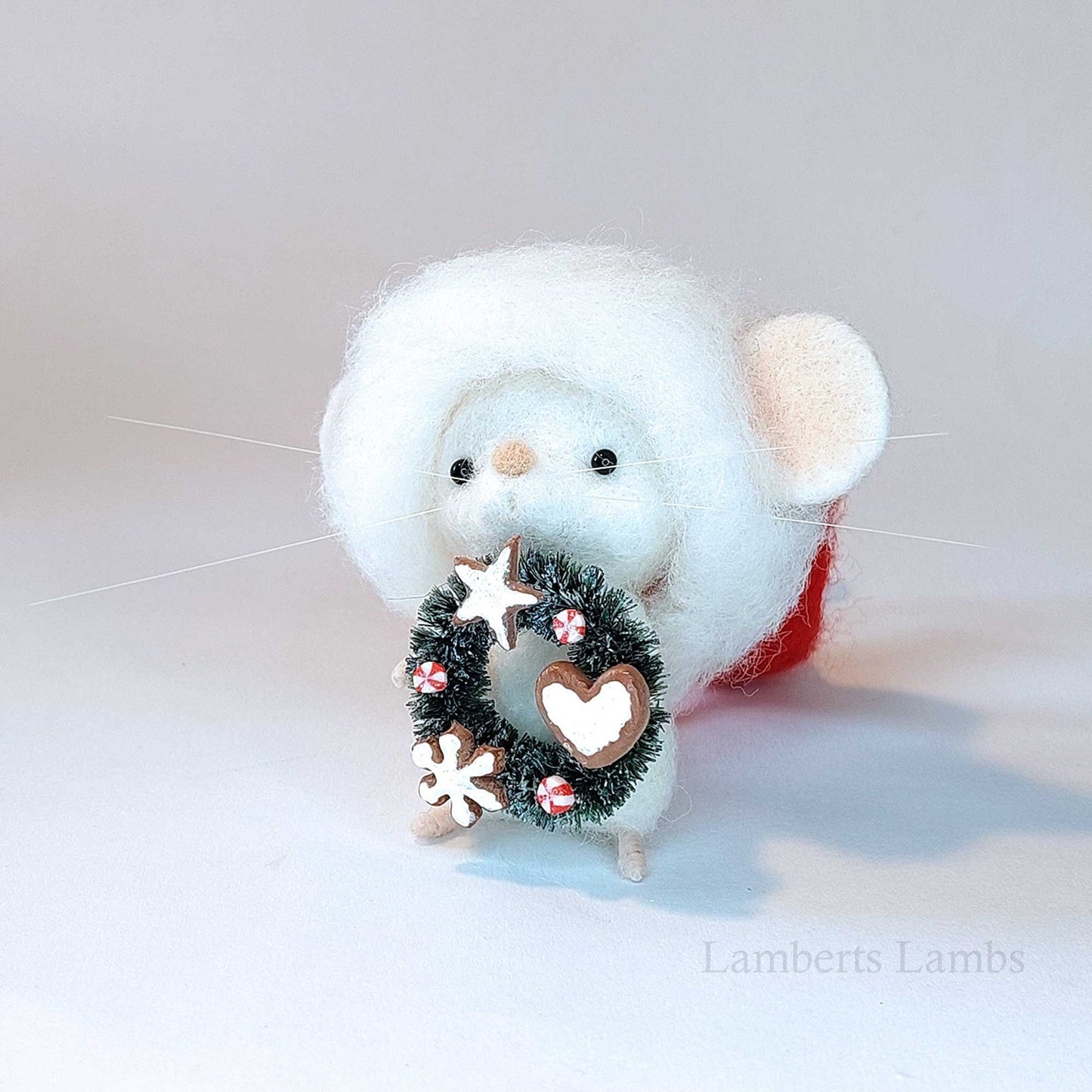 Adorable needle felted Christmas mouse in a Santa hat holding a wreath decorated with cookies/ White wool felted mouse keepsake decoration