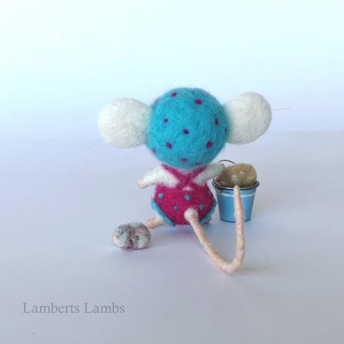 White needle felted mouse in a one piece pink swimsuit with blue pok-a-dots and beach pail